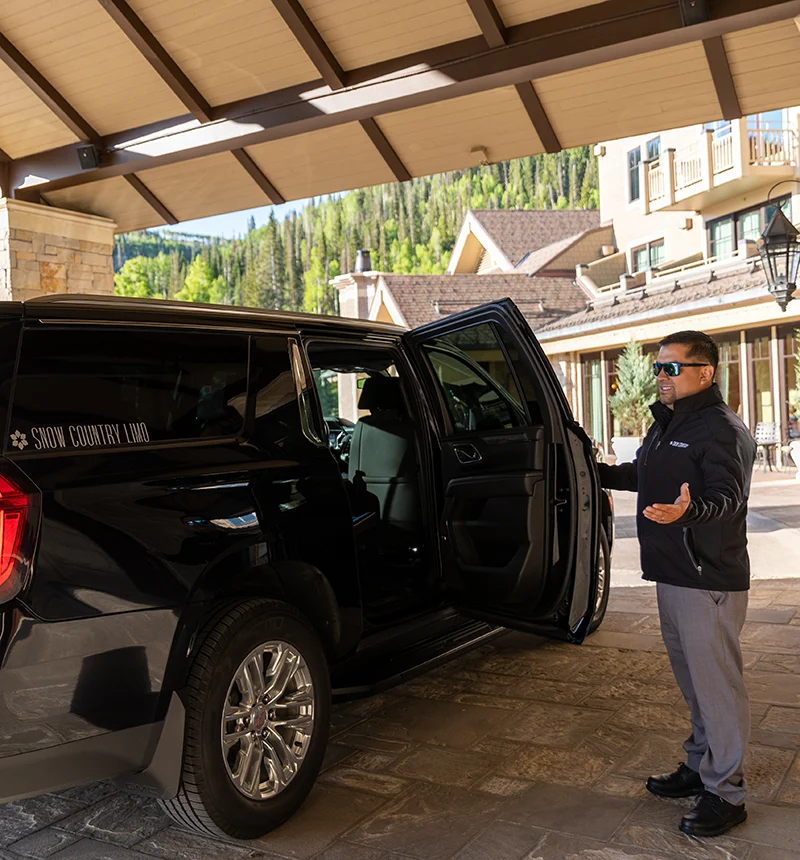 A driver for Snow Country opens the door for a guest