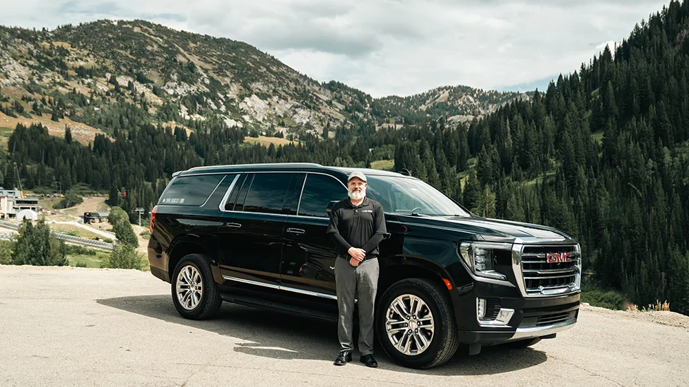 A Snow Country driver stands next to his SUV