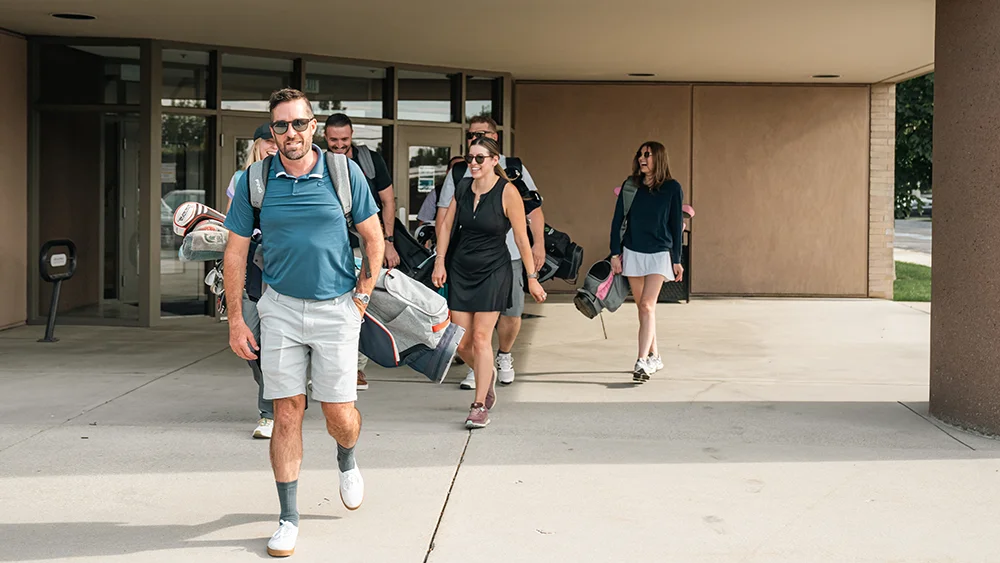 A team leaves their hotel with golf clubs