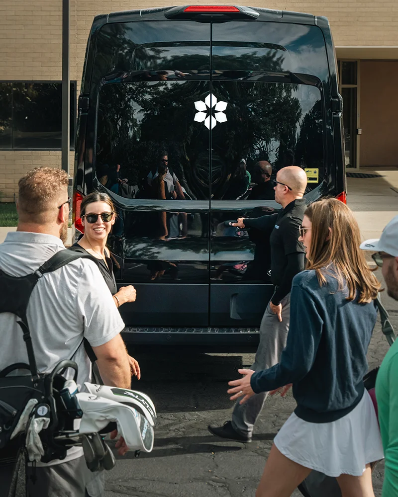 Employees on a retreat load golf clubs into a Snow Country van