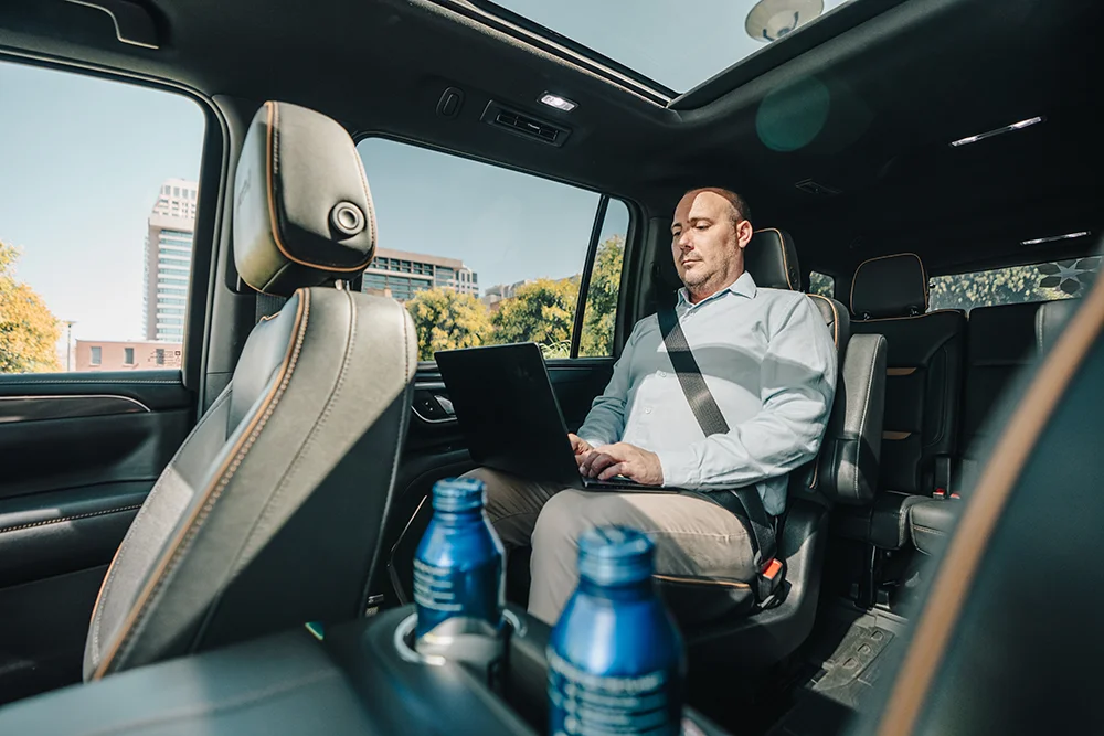 A passenger in a Snow Country SUV uses his laptop