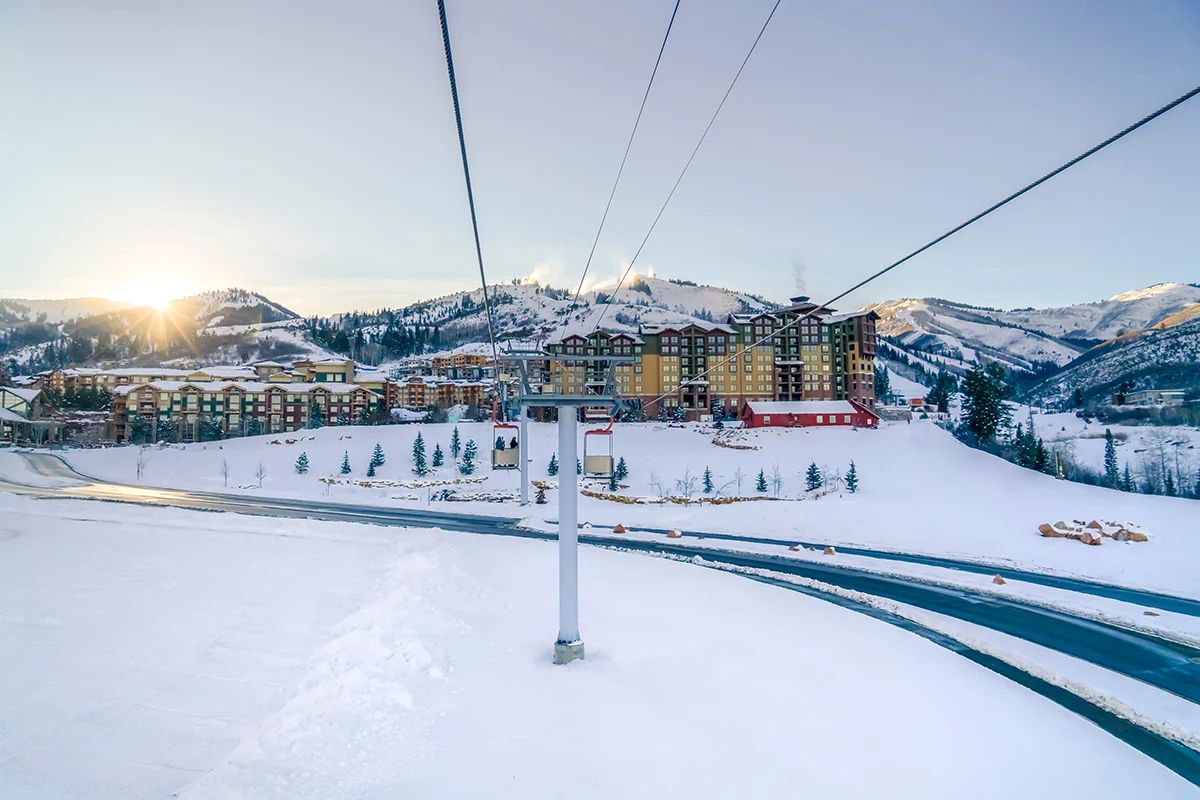 view of a chair lift with lodging in the background.