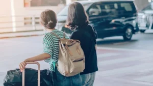 Two passengers with luggage waiting curbside for a pick up shuttle
