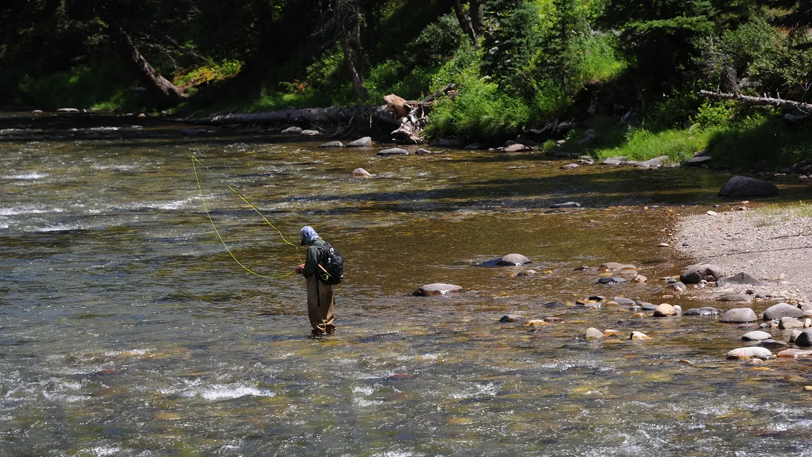 Person fly fishing in Gallatin Valley river, a great activity to pursue during shoulder season luxury travel in Utah, Montana, or Colorado