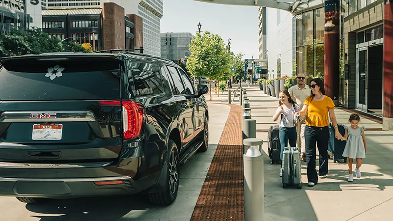 A family boards a Snow Country SUV outside their hotel