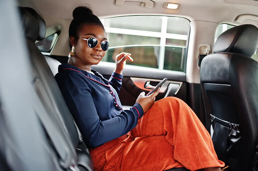 Well-dressed black woman in the back of a private car