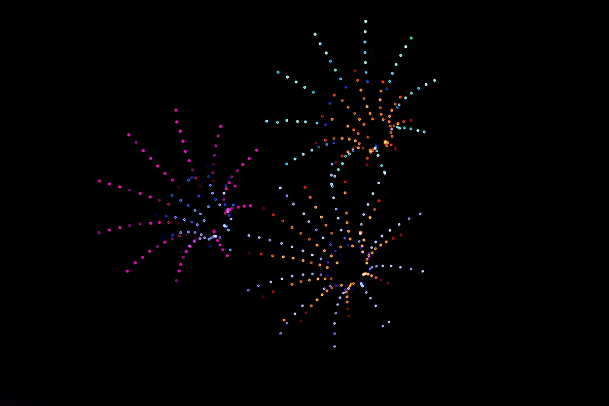three bursts of drone lights that mimic traditional fireworks in a night sky