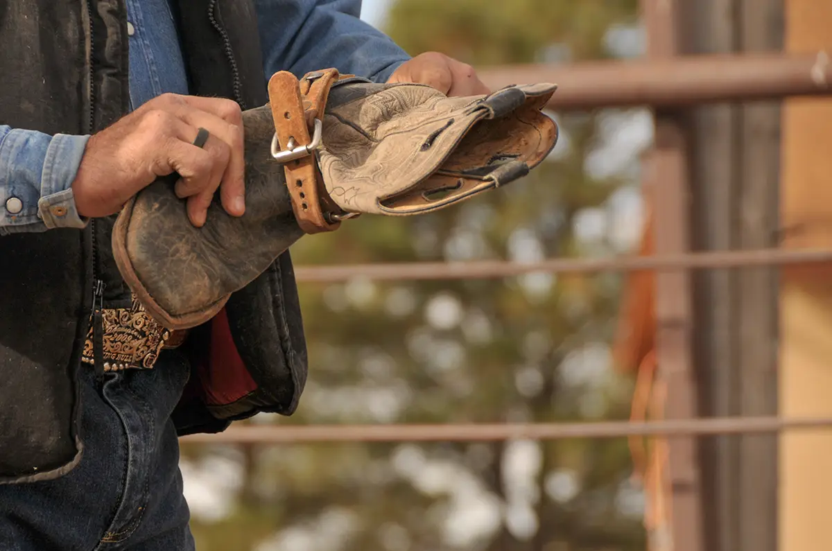 a man's hands holding a leather cowboy boot