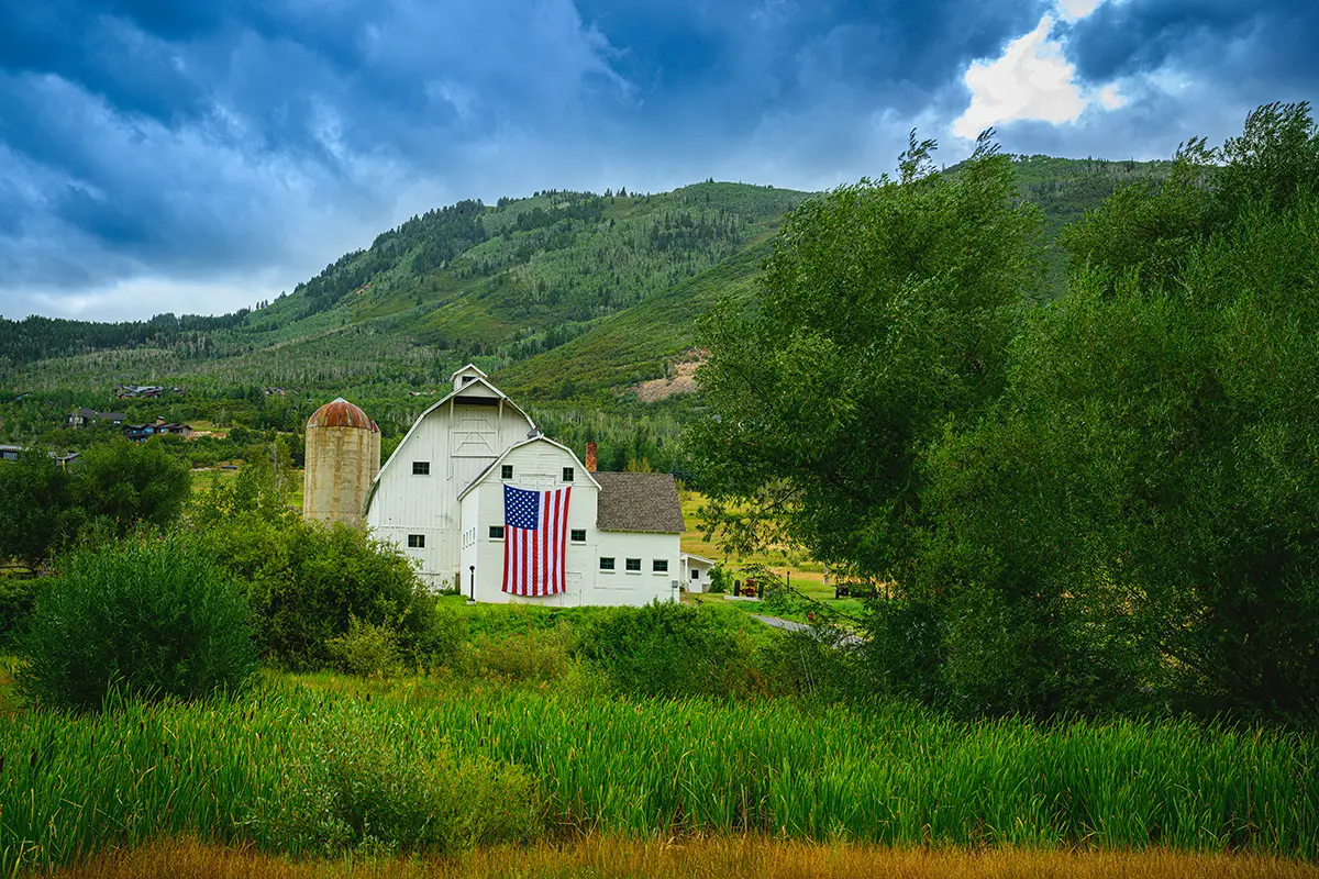 Historic white barn in Park City with a United States flag hanging on the side for Park City 4th of July