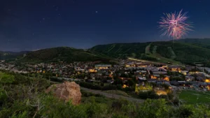 Park City 4th of July fireworks in the night sky over a dimly lit mountain town