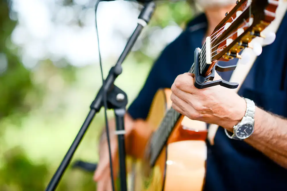 closeup detail of hand playing folk guitar outdoor summer festival